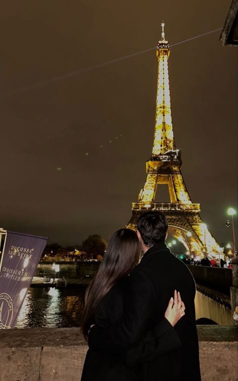Couple embracing by the Seine River with the illuminated Eiffel Tower at night in Paris. Perfect romantic getaway.