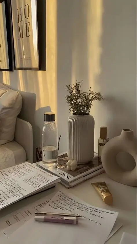 Cozy home office setup with notes, water bottle, vase with flowers, and soft lighting. Perfect for productivity and relaxation.