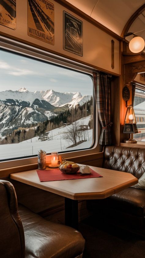 Cozy train dining area with mountains visible outside; table set with candle and fruit bowl, offering a scenic winter journey ambiance.