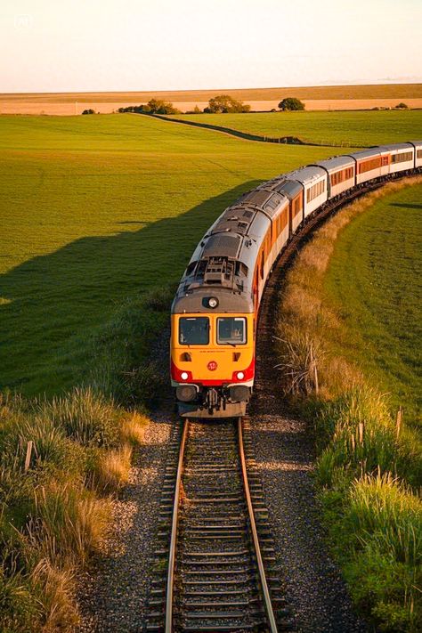 Train on a scenic curve with green fields and sunset lighting, highlighting travel and nature's beauty. Perfect for travel enthusiasts.