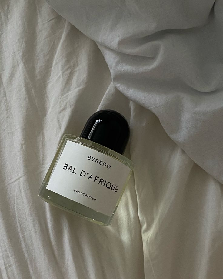 Byredo Bal D'Afrique perfume bottle on white linen sheets, capturing elegance and luxury fragrance design.