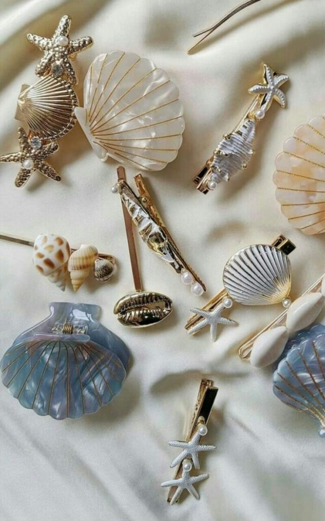1ae1b431-843f-47e7-a0ee-ad5a0c33f2d3 - Handy Home Elegant seashell and starfish hair accessories on a silky fabric background, showcasing coastal-themed designs with pearls and gold accents.