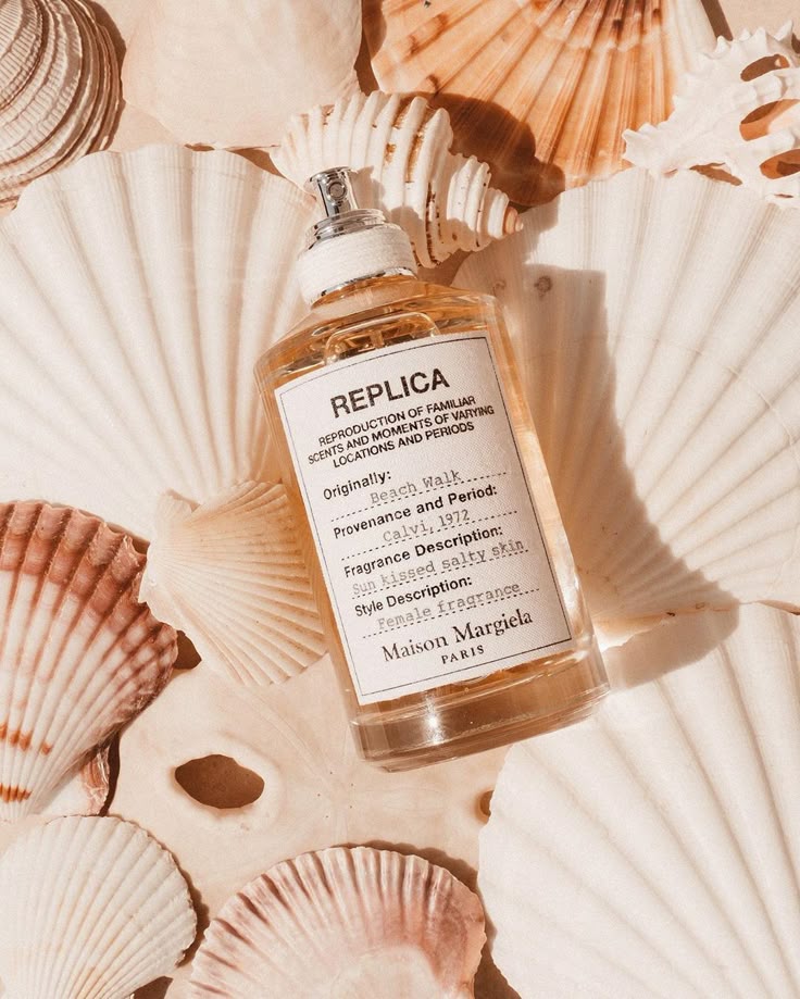 Perfume bottle of Maison Margiela Replica Beach Walk surrounded by seashells, evoking summer and seaside vibes.