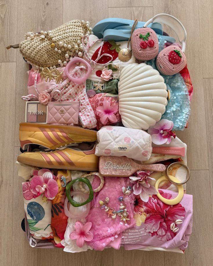 Colorful assortment of fashion accessories and clothing items, including handbags, jewelry, shoes, and floral designs, on wooden floor.