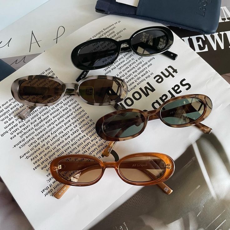 Four stylish oval sunglasses on open magazine pages, showcasing chic eyewear fashion and trends.