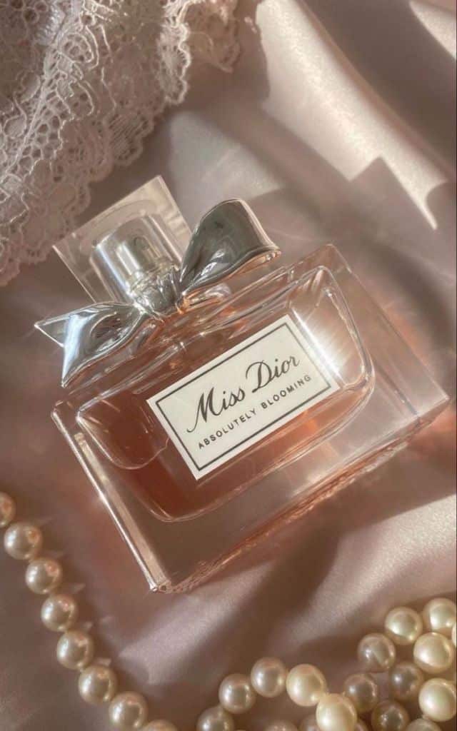 10 Lasting Perfumes That Are Perfect for Classic Brides - Handy Home Miss Dior Absolutely Blooming perfume bottle on pink satin with lace and pearls, exuding elegance and luxury.