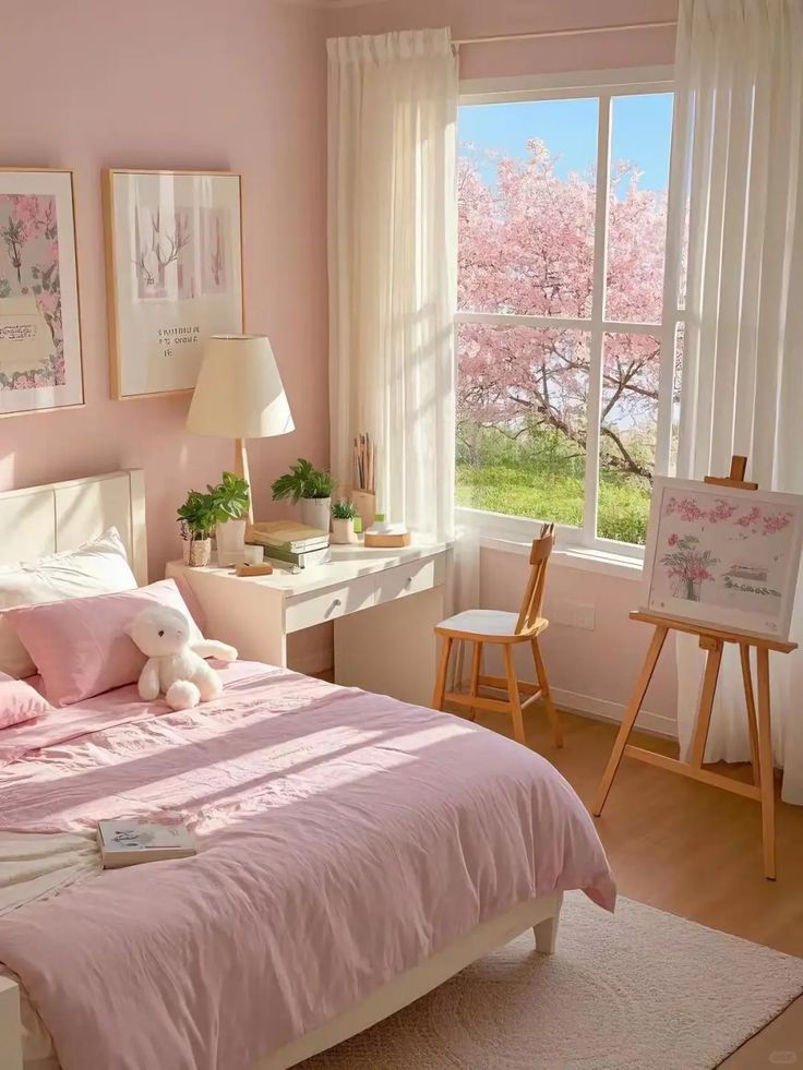 Cozy pastel pink bedroom with a window view of cherry blossoms, featuring a soft bed, desk, chair, and decorative plants.