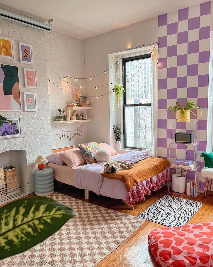 Cozy bedroom with vibrant decor, featuring a checkered wall, plush bed, and indoor plants by a large window with city view.