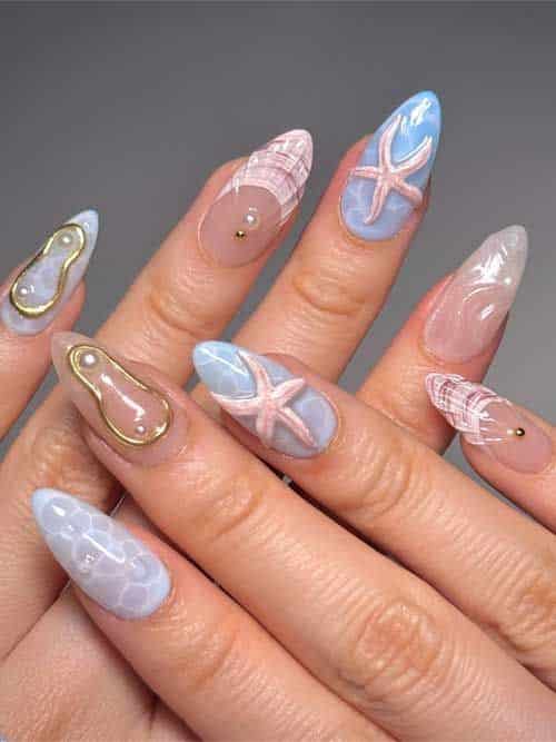 25 Irresistible Seashell Nails Ideas to Try ASAP - Handy Home Ocean-themed nail art with starfish and shells on pastel colors. Intricate, creative nail design with gold accents.