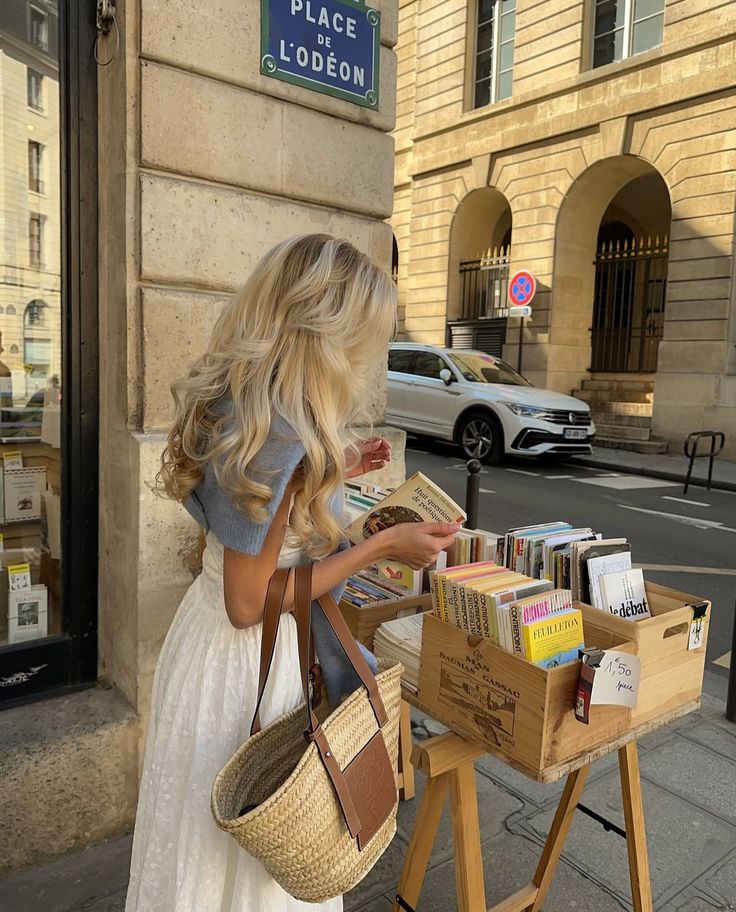 Woman browsing books at an outdoor stand in Paris near Place de l'Odéon. Street scene with vintage charm.