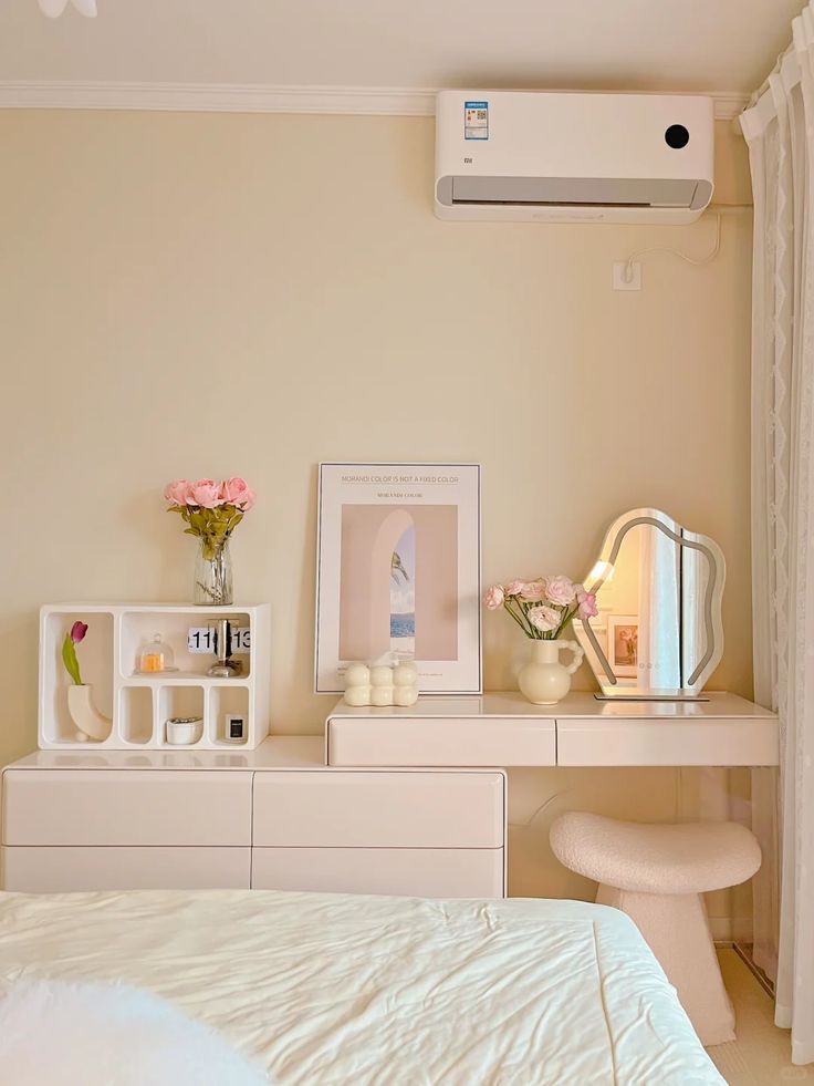 Minimalist bedroom with vanity, mirror, flowers, and modern decor. Air conditioner above. Cozy and elegant interior design.