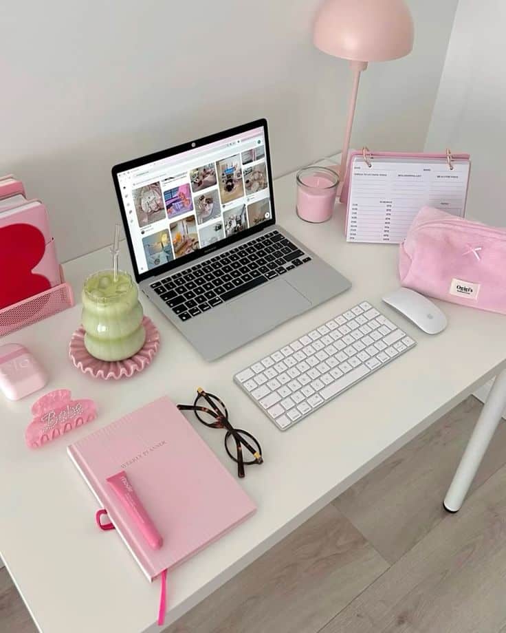 Chic pink-themed workspace with a laptop, planner, lamp, and accessories. Modern feminine desk setup for productivity and style.
