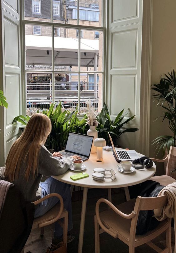 Cozy workspace with laptops, plants, and a window view; perfect for remote work and productivity.
