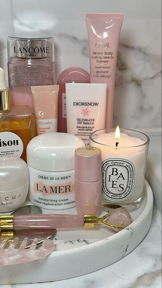 Luxurious skincare products and candle in a marble bathroom setting, featuring Lancome, La Mer, and Glossier.