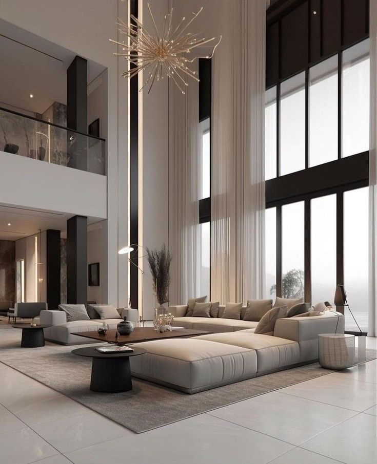 Luxurious modern living room with high ceilings, large windows, neutral-toned sofas, and a chic chandelier for elegant ambiance.