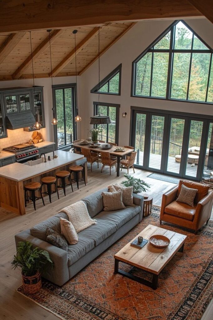 Spacious modern living room with rustic decor, large windows, cozy seating, and open kitchen dining area overlooking nature.