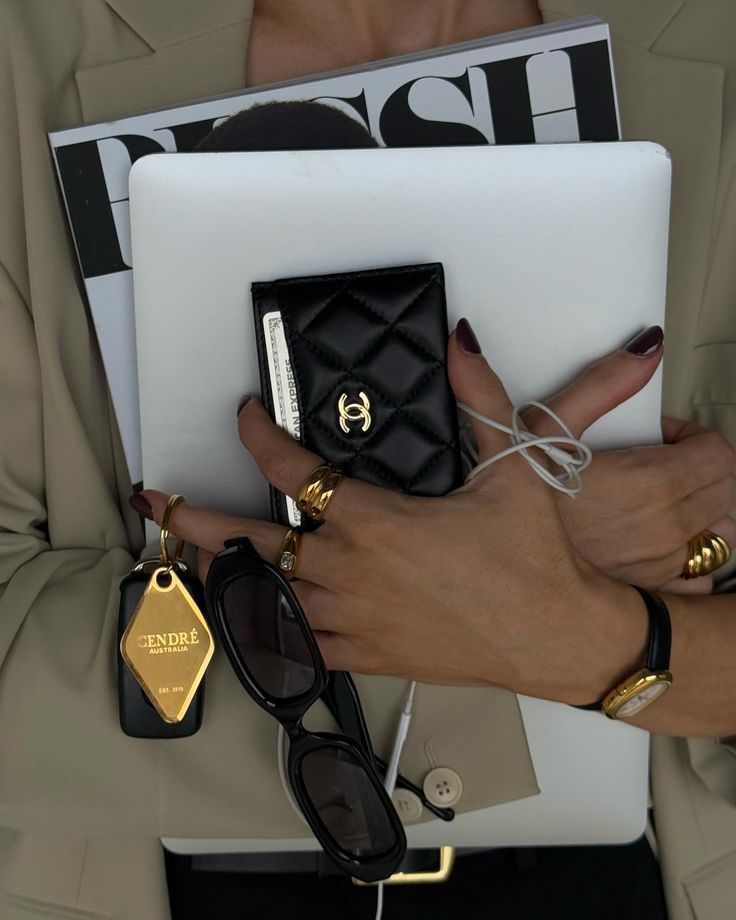 Fashionable woman holding a magazine, tablet, luxury wallet, and accessories, showcasing chic style and elegance.