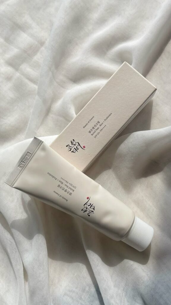 Korean beauty sunscreen tube with box on a soft white cloth, emphasizing SPF protection and probiotics benefits.
