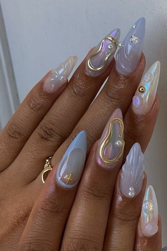 Iridescent 3D nail art featuring pearl accents and gold details on stiletto-shaped nails.