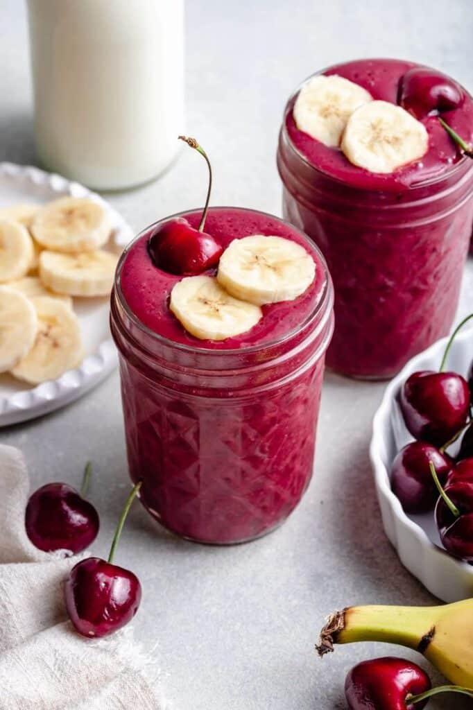 Refreshing cherry banana smoothie in mason jars with fresh fruit garnish. Healthy and vibrant summer treat, perfect for breakfast.