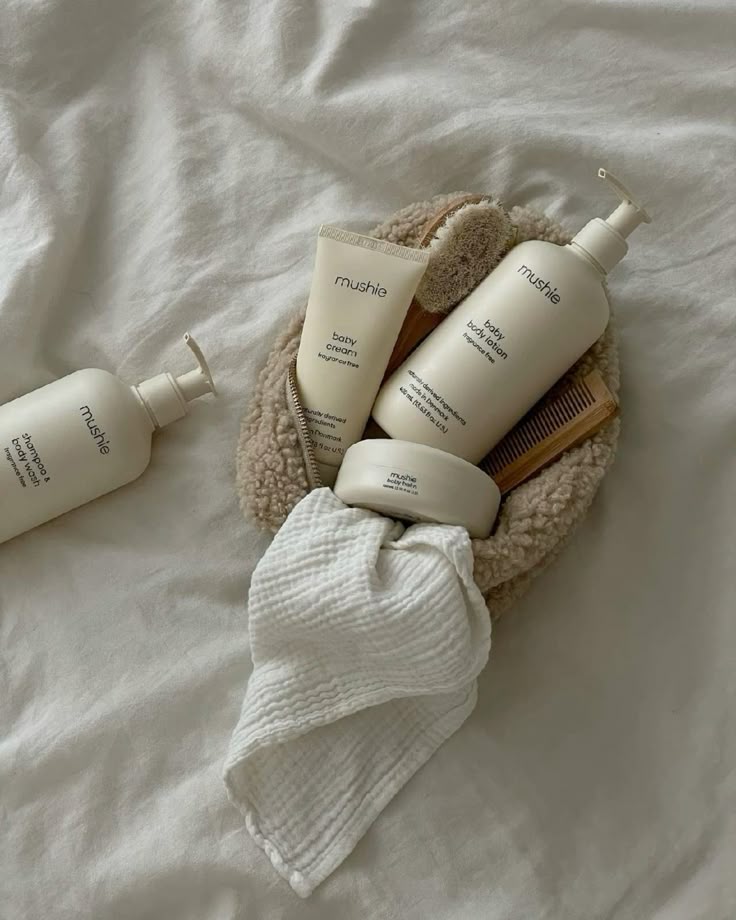 Natural baby skincare products and accessories on soft fabric, including lotion, cream, and brush, perfect for gentle infant care.