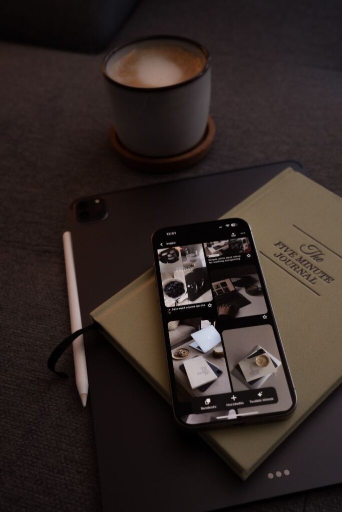 Coffee beside a journal, tablet, and smartphone on a grey sofa, perfect for a cozy and productive morning routine setup.