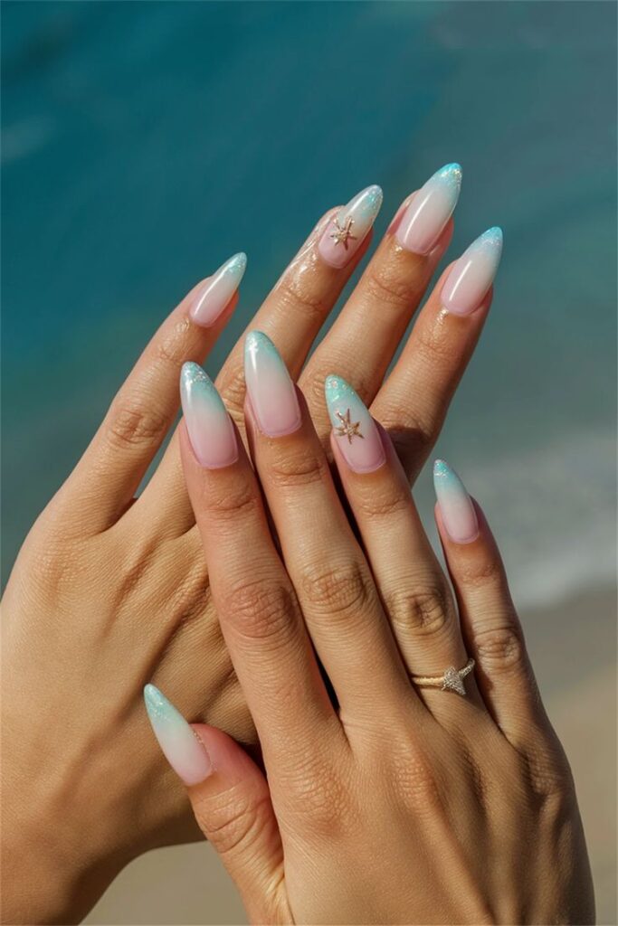 Elegant pastel gradient nails with starfish design, perfect for a beach-inspired manicure. Close-up of hands with a delicate ring.