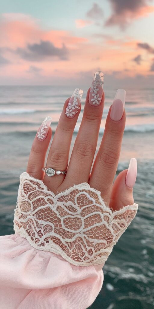 Elegant hand with floral nail art and lace sleeve against a serene ocean sunset. Perfect for fashion or beauty themes.