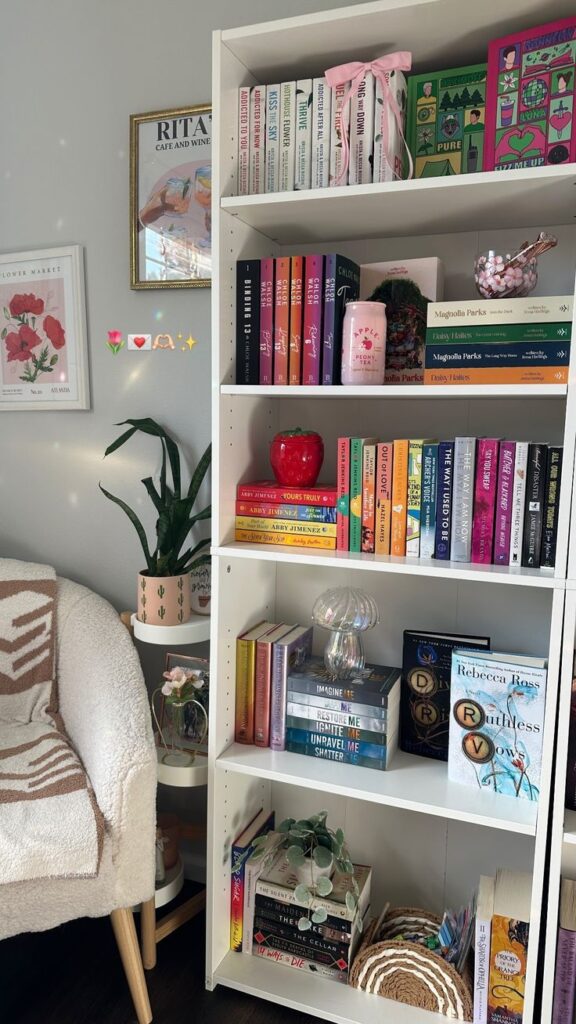 Cozy reading nook with a white bookshelf filled with colorful books, plants, and decor. Bright and inviting literary space.