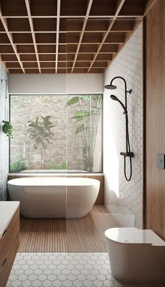 Modern bathroom with freestanding bathtub, glass panel shower, wood accents, and scenic garden view through large window.