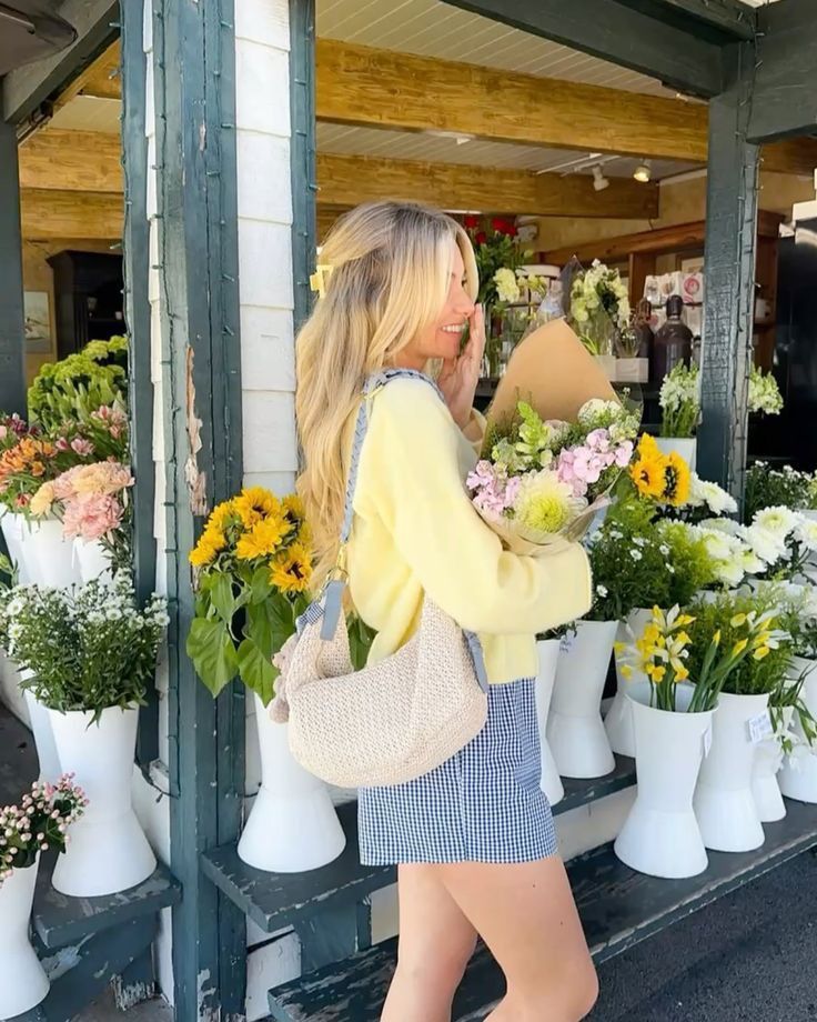 A woman joyfully holds a bouquet of flowers outside a charming flower shop, surrounded by colorful blooms and rustic decor.