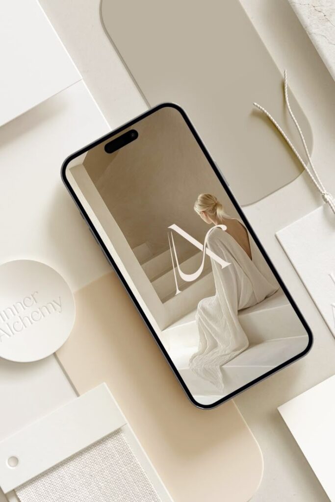 Smartphone displaying a minimalist design with a woman in white, surrounded by white and beige samples. Modern elegance concept.