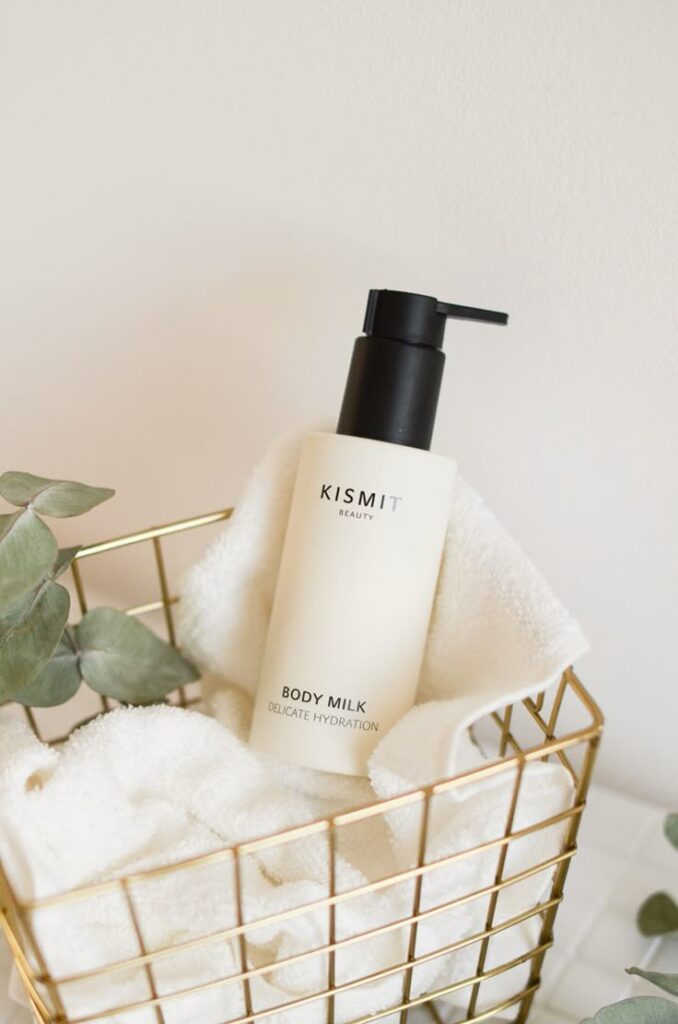 Hydrating body milk in a sleek pump bottle placed in a gold wire basket lined with towels, offering delicate skincare.