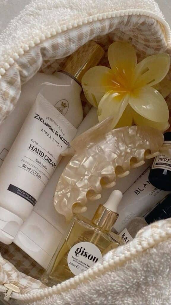 Cosmetic essentials in a pouch: hand cream, hair oil, flower clip, hand soap. Ideal for travel and self-care routines.