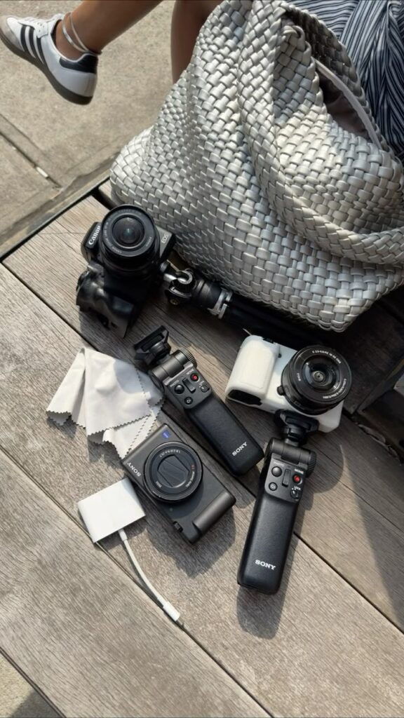 Photography gear setup with cameras, lens, tripod, and bag on a wooden surface. Perfect for travel and outdoor shoots.