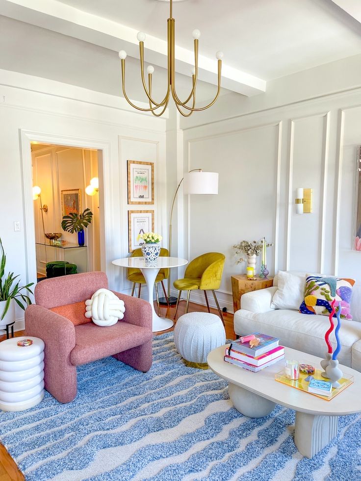 Modern living room with colorful decor, elegant chandelier, cozy seating, and vibrant accents, creating a stylish and inviting atmosphere.