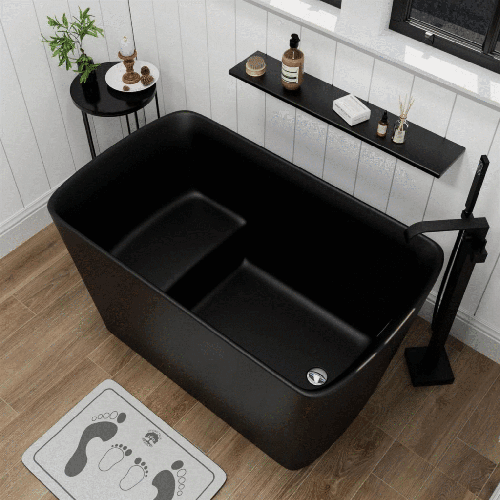 Modern black bathtub in a stylish bathroom with wood flooring and minimalist decor elements.