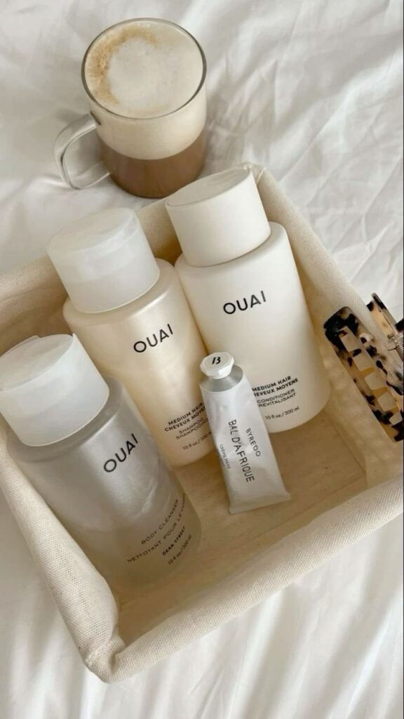 OUAI haircare products in a basket with a cup of coffee on a white bed, perfect for morning self-care rituals.