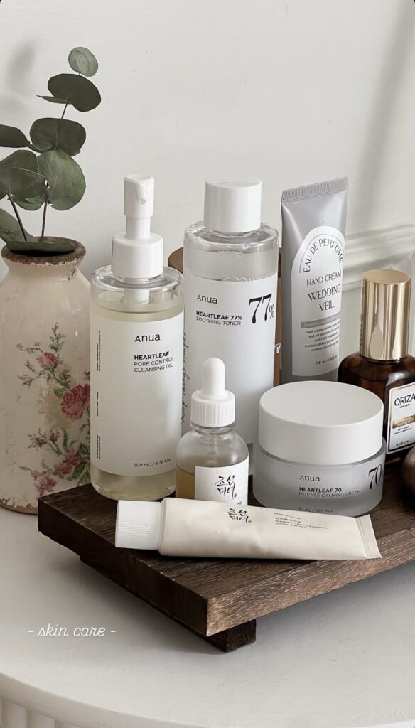 Skincare products displayed with plants, featuring cleansing oil, toner, hand cream, and calming cream on a wooden tray.