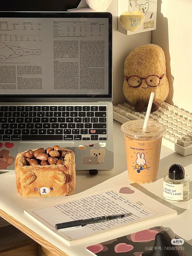 Cozy workspace with laptop, coffee, notes, plush toy, and nut holder. Perfect for studying or working in comfort and warmth.