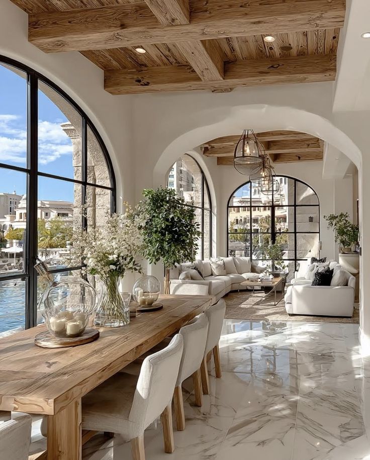 Screenshot - Handy Home Luxurious open-plan living room with waterfront views, rustic wooden beams, elegant marble floors, and cozy seating area.