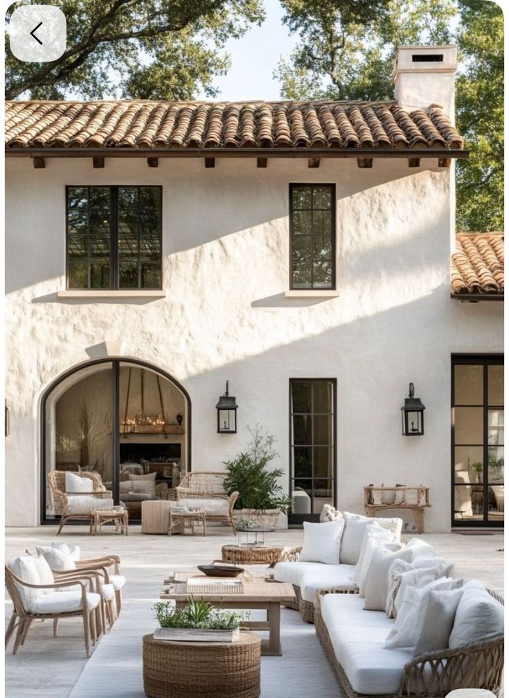 6b170f45-972a-4ab9-88ae-4094774315f9 - Handy Home Mediterranean-style patio with wicker furniture, white cushions, and lush greenery, perfect for outdoor relaxation and gatherings.