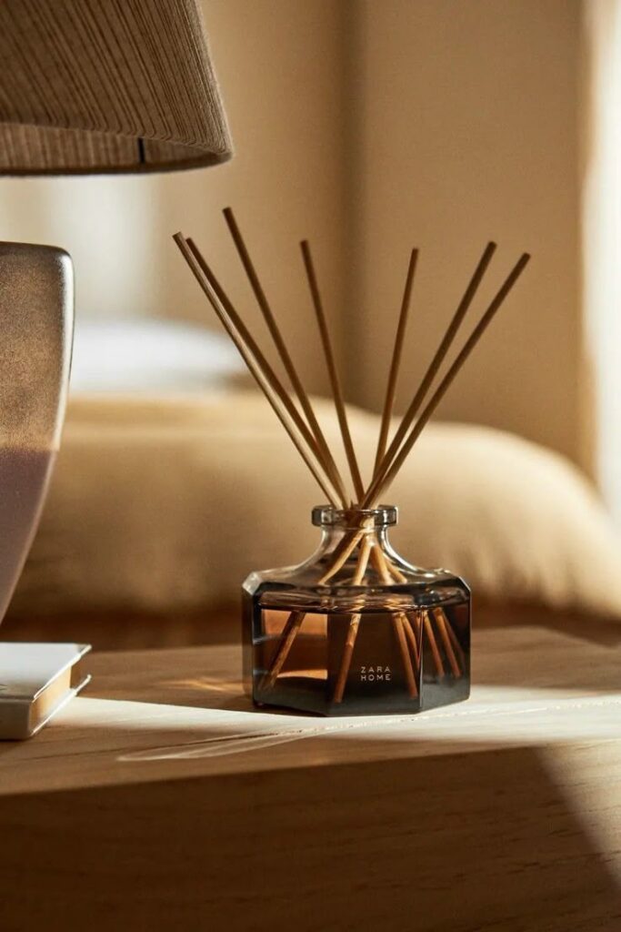 Reed diffuser on a wooden table, adding a cozy touch to modern home decor. Warm lighting enhances the elegant ambiance.