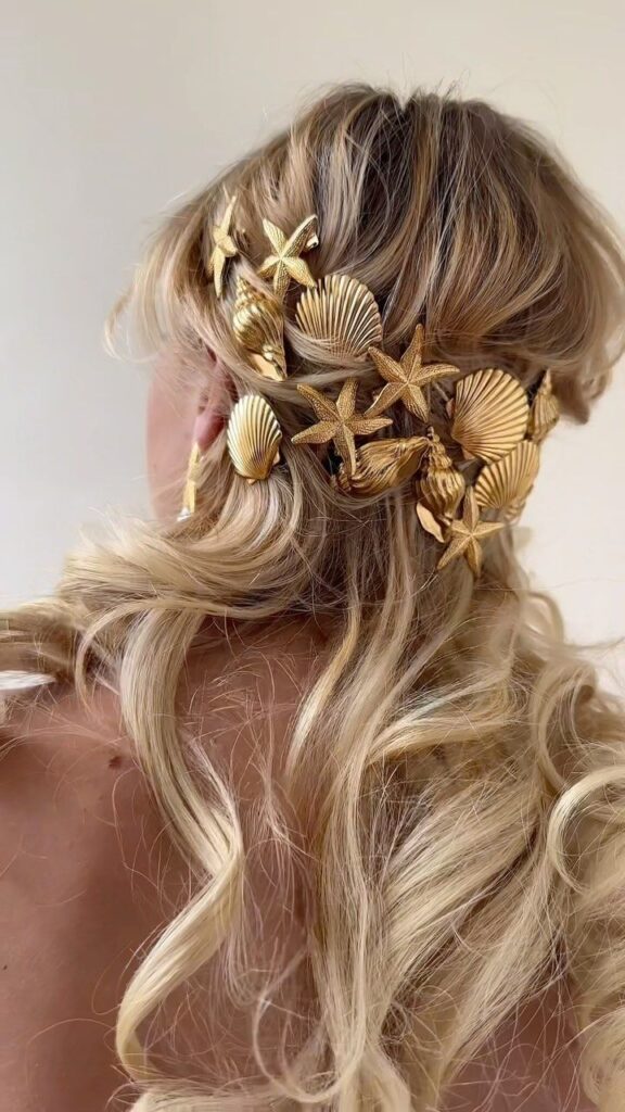 Blonde hair styled with seashell and starfish gold accessories, creating an elegant, beach-inspired look.