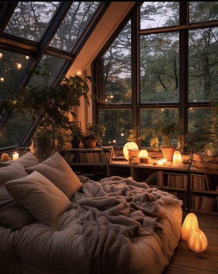 Cozy bedroom with large windows, soft bedding, warm lighting, and plants, creating a serene and inviting atmosphere.