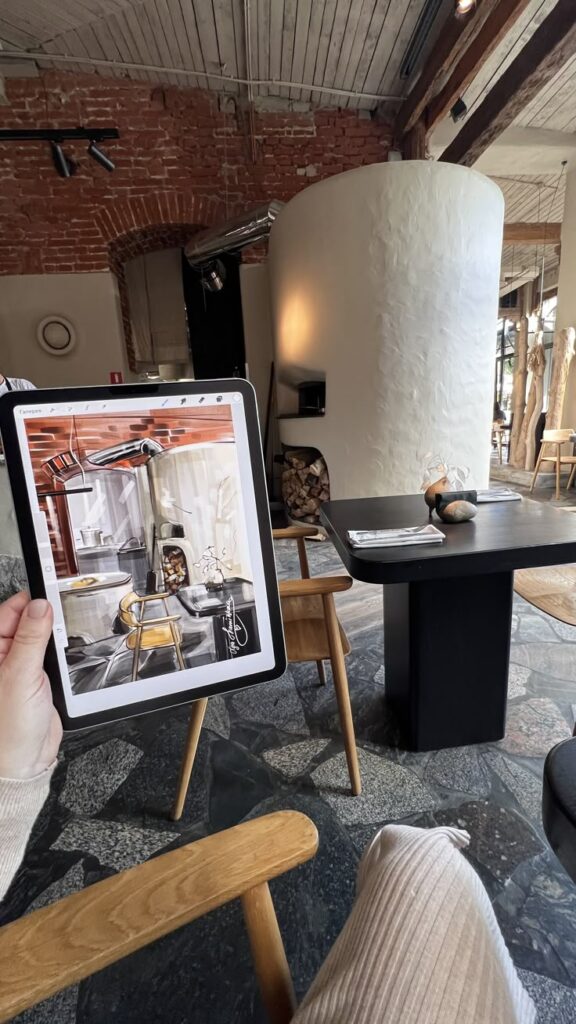 Tablet displaying a detailed interior sketch of a stylish cafe, matching the real-life cafe setting with rustic and modern decor.