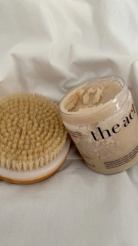 Dry brush and body scrub on white fabric for exfoliating skin care routine.
