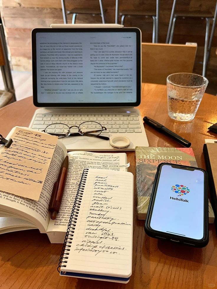 Tablet and smartphone on a café table with books, glasses, and a notepad. Scene of study and work, cozy atmosphere.