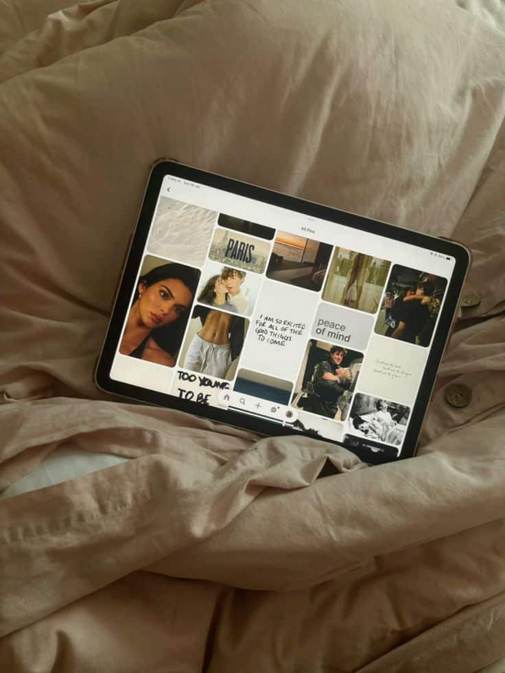 Tablet on a bed displaying mood board with quotes, cityscape, and portraits, conveying a relaxed and inspirational atmosphere.