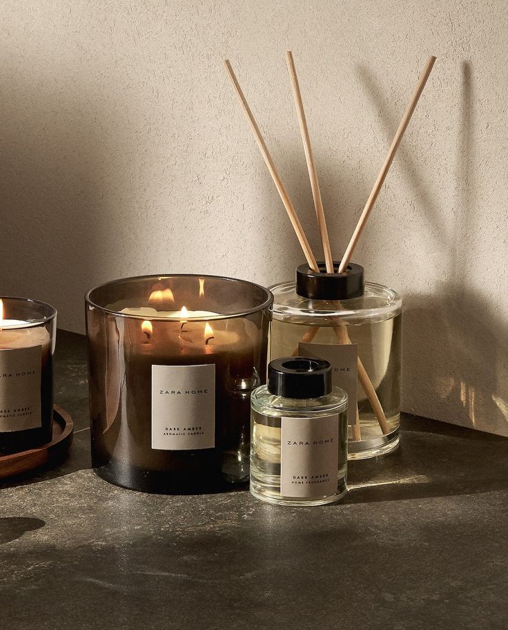 Lit candle and reed diffuser set on a table, creating a cozy, aromatic ambiance in a modern home setting.